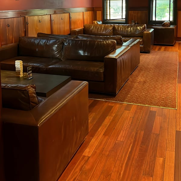 Lola's bar lounge area with brown leather sofas, dark wood tables, and a brown rug.